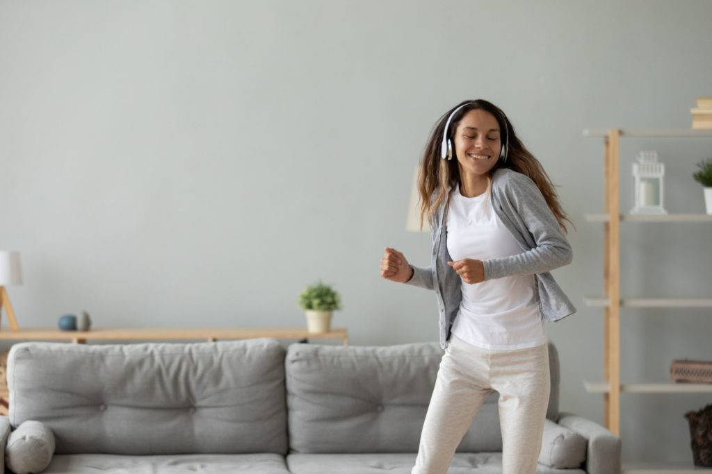 Overjoyed young woman listen to music dancing at home